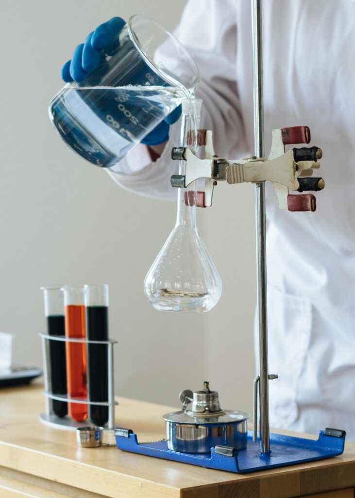 pexels-photo-3825379-3825379 Scientist pouring liquid into a flask in a laboratory setting for research.