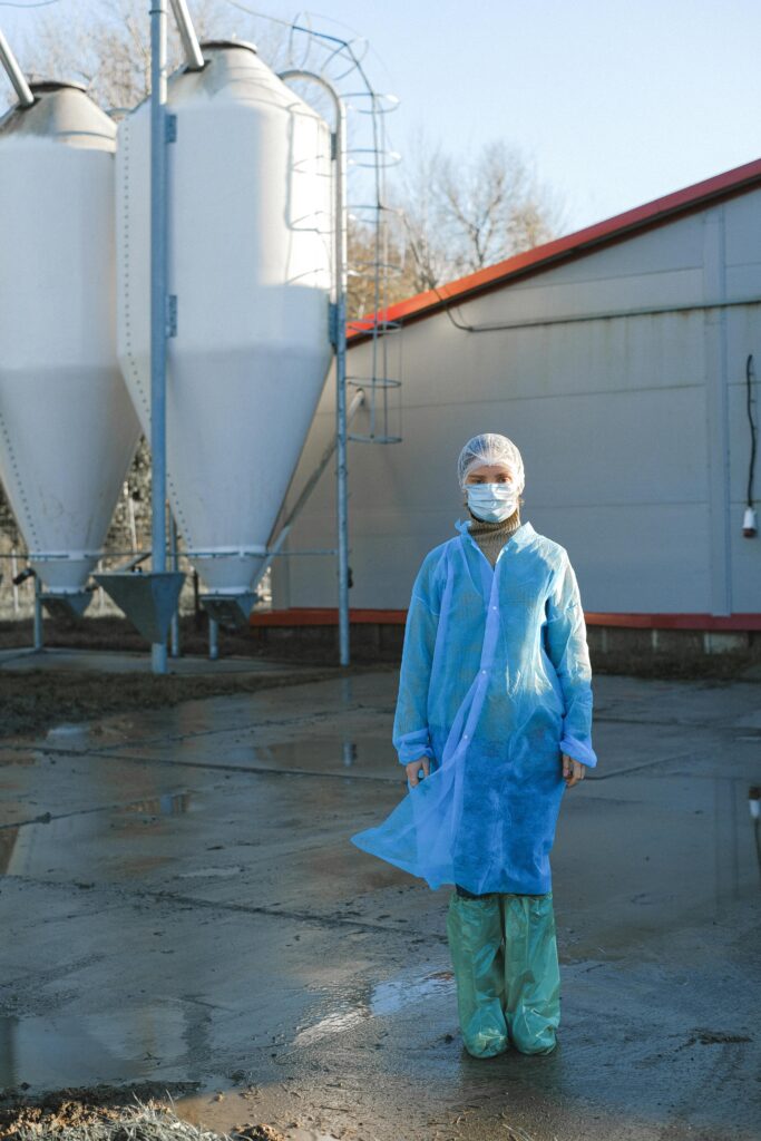 A worker in safety gear stands outside an industrial facility, emphasizing sanitation and safety.